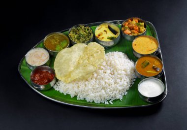 Canlı bir Güney Hint thali 'si. İçinde pirinç, haşhaş ve muz yaprağı üzerinde servis edilen çeşitli sebze körisi var. Bu geleneksel yemek Hint mutfağının zengin lezzetlerini ve çeşitli malzemelerini sergiliyor..