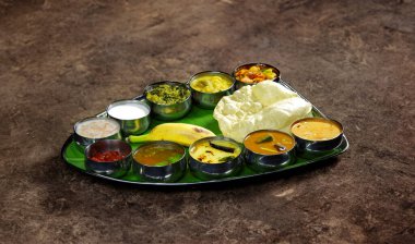 An appetizing Indian vegetarian thali served on a banana leaf, featuring diverse curries, papadum, rice, and condiments on a brown textured background. Perfect for illustrating cultural cuisine and dining experiences. clipart