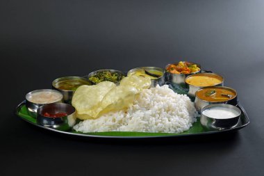 Muz yaprağında çeşitli köri, pirinç ve papadum içeren canlı bir Güney Hint thali otantik Hint mutfağı ve yemek kültürü sunar..