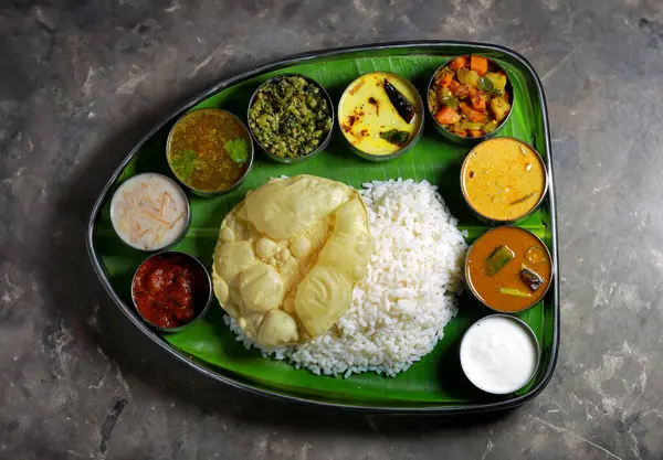Canlı bir Güney Hindistan vejetaryen thali. İçinde pilav, köri ve papaddan oluşan muz yaprağı var. Bu geleneksel yemek otantik tatlar ve çeşitli renkli yemekler sunar..