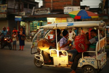 Canlı bir akşam sokak sahnesinde kalabalık bir şehir bölgesinde yolcuları taşıyan renkli bir çekçek yerel hayatın ve kültürel ulaşımın özünü yakalıyor. Batı Bengal 9-16-2018