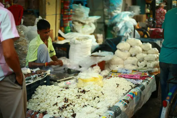 Bir satıcının çeşitli geleneksel Hint atıştırmalıkları sattığı yerel bir market sahnesi. Sahne, Hint pazarının canlı atmosferini ve kültürel zenginliğini yansıtıyor. Batı Bengal 9-16-2018