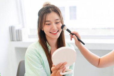 Güzellik ve kozmetik konsepti, makyaj sanatçısı yanağında kızarıklık ve makyajla fırça kullanıyor.. 