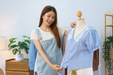 Online shopping concept, Asian women measure length of shirt to present and sell in streaming video.