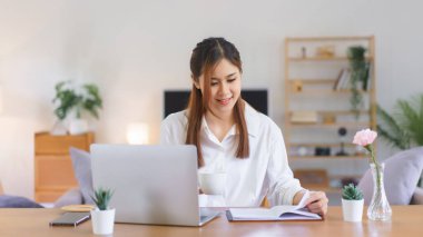 Rahatlatıcı zaman kavramı, kadınlar kahve içip kitap okurken modern ev ofisinde çalışıyorlar..