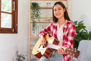 Guitar and singer concept, Young woman learning and practice playing chords with acoustic guitar.