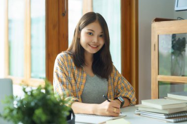 Education and literacy concept, College student girl using laptop and doing homework in library.