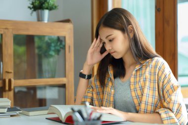 Education and literacy concept, College student girl feel confused while reading a book in library.