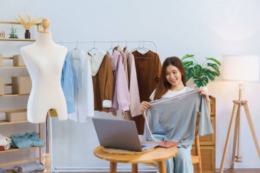 Online shopping concept, Young Asian women is selling and present clothes detail on video streaming.