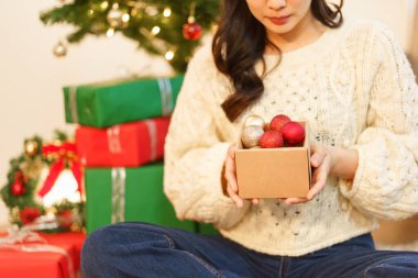 Noel kutlaması konsepti, Noel Baba şapkalı Asyalı kadın süsleme için bir kutu Noel balosu tutuyor..