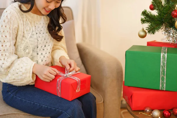 Christmas concept, Asian woman sitting in christmas decorated living room and open christmas gift.