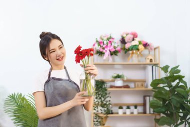 Çiçekçi konsepti, elinde kırmızı gerbera vazosu olan kadın çiçekçi müşteriye göndermeye hazırlanıyor..