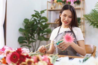 Çiçekçi konsepti, çiçek vazosu yapmak için Gerbera 'yı makasla kesen kadın çiçekçi..