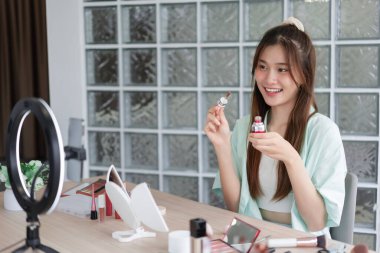 Güzellik blogcusu konsepti, Vlog için ürün ve kayıt videosu tanıtmak için serumu gösteren genç kadın.