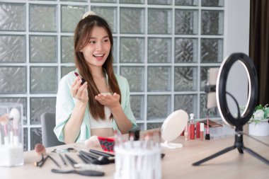 Beauty Vlogger konsepti, Vlog için ürün ve kayıt videosu sunmak için ruj tutan genç kadın..