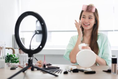 Güzellik sitesi konsepti, genç bir kadının Vlog 'a ürün tanıtmak için yüzüne nemlendirici krem sürmesi..