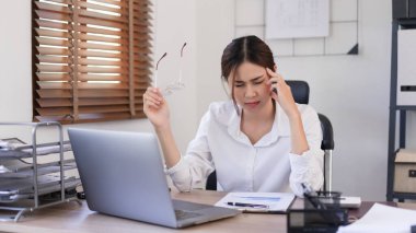 İş dünyası konsepti, iş kadını iş sonrası yorgun ve baş ağrısı çekerken gözlük tutuyor..