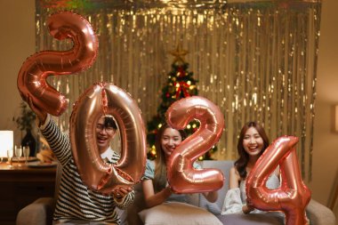 Yeni yıl partisi konsepti, arkadaş grubu yeni yıl partisinde 2024 numaralı pembe balonu tutuyor..