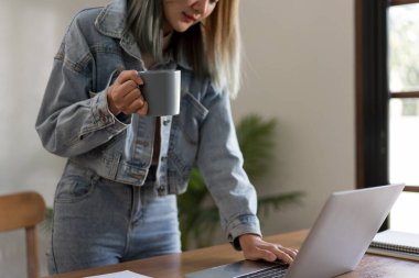 Yaratıcı tasarım konsepti, kadın tasarımcının müşteriye ulaşmak için dizüstü bilgisayarda çalışırken kahve içmesi.
