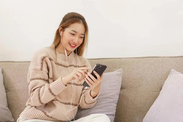 Leisure time concept, Women wear earphone to surfing social media and listening music on smartphone.