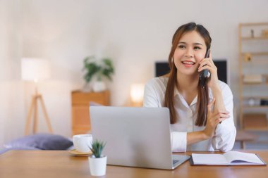 Rahatlatıcı zaman kavramı, akıllı telefondan konuşan ve modern ofis bilgisayarında çalışan kadınlar..