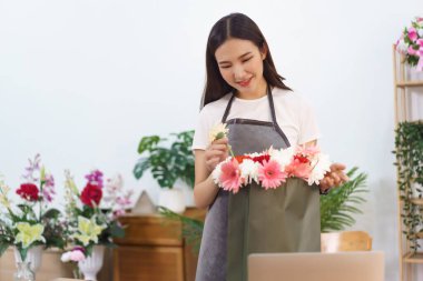 Çiçekçi konsepti, kadın çiçekçi kasımpatı ve Gerbera çiçek buketini alışveriş poşetinde yapıyor..