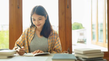 Eğitim ve okur yazarlık kavramı, kolej öğrencisi kız ders kâğıtlarını okur ve deftere not alır..