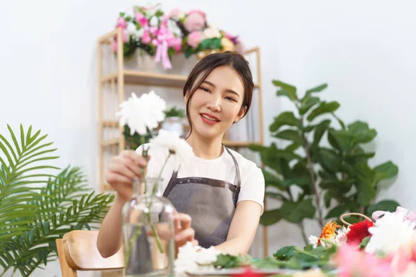 Florist concept, Female florist arrange white chrysanthemum in vase with happiness in flower shop.