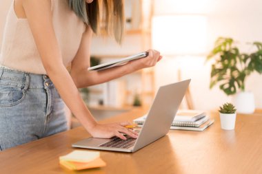 Creative design concept, Female designer drawing new collection clothes and checking data on laptop.