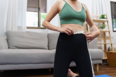 Sağlıklı ve kilo verme konsepti, genç Asyalı kadın kemerini mezurayla ölçüyor..