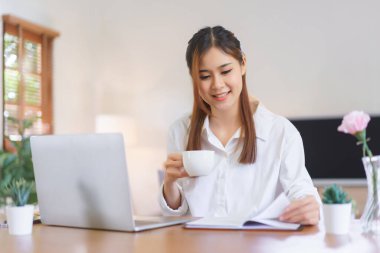 Working at home concept, Women drinking coffee and reading book while working at modern home office.