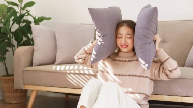 Dinlenme zamanı konsepti, kadınlar yerde oturup yastıkla kulaklarını kapatırken stresli ve üzgün..