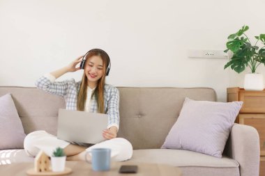 Leisure time concept, Women sitting on comfortable couch and wearing headphone to watching movie.