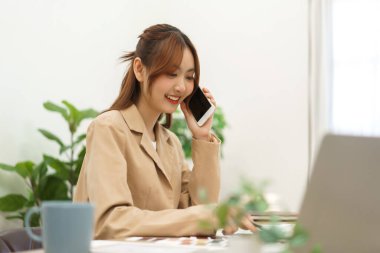 Architecture concept, Female architect designing house interior and talking with client on phone.