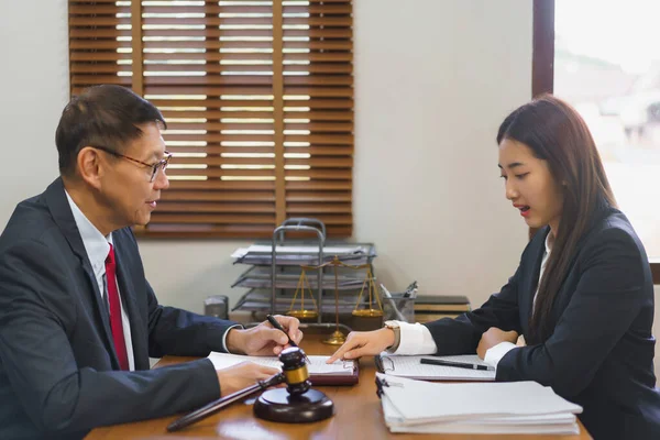 Legal and justice concept, Young female lawyer pointing on contract to consulting senior lawyer.