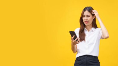 Women feel confused while reading data on smartphone with empty space on isolated yellow background.