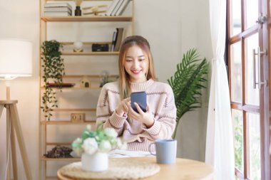 Leisure time concept, Women use smartphone to surfing social media while relaxation in living room.