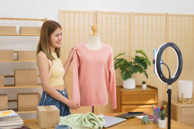 Online merchant concept, Fashion designer presenting and selling sweater to client in live stream.