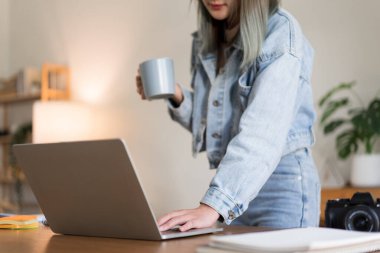 Yaratıcı tasarım konsepti, kadın tasarımcının müşteriye ulaşmak için dizüstü bilgisayarda çalışırken kahve içmesi.