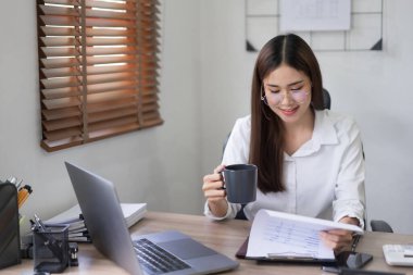 İş konsepti, İş kadını ofiste iş belgesi okurken kahve içiyor.