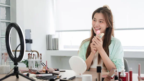 Beauty blogger concept, Young woman presenting different makeup brush and introduce product on Vlog.