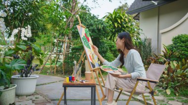 Creative art concept, Female artist painting on canvas with brush and watercolor in outdoor garden. clipart