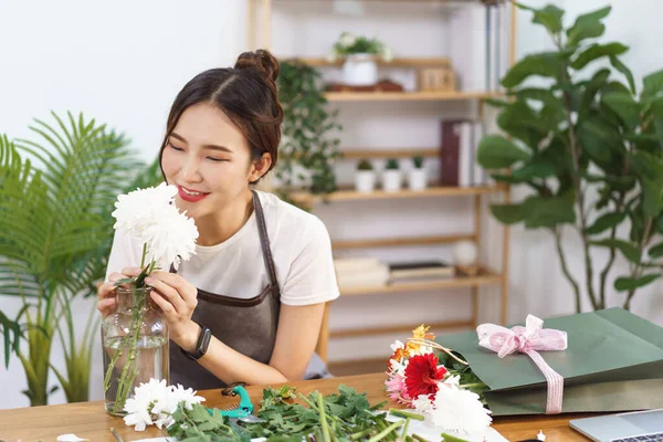 Stock image Flower shop concept, Female florist smile and smells of white chrysanthemums in vase with happiness.