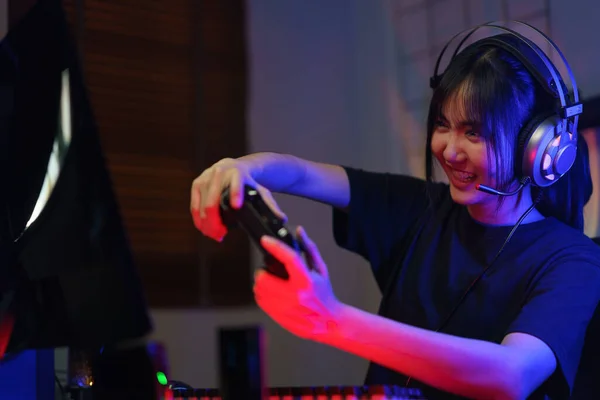 ヘッドフォンで女性サイバーハッカーゲーマーネオンライトでジョイスティックとコンピュータ上でビデオゲームをプレイ — ストック写真