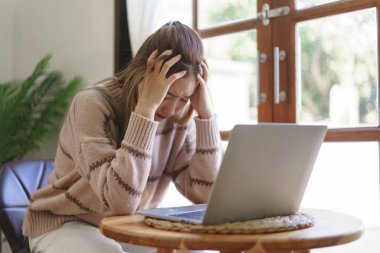 Rest time concept, Women suffering headache and stressful while working on laptop in living room.