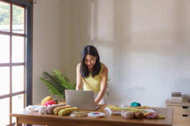 Dikiş işi konsepti, dizüstü bilgisayarda çalışan ve yumruk iğnesiyle el işi nakış yapan kadınlar..