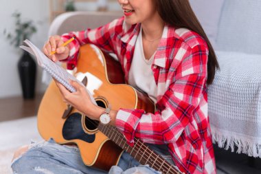 Gitar ve şarkıcı konsepti, genç kadın yerde akustik gitar çalarken şarkı bestelemekte..