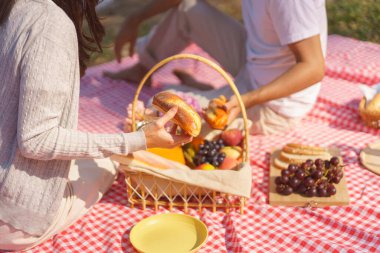 Birbirlerine aşık genç bir çift parkta, göl kenarında piknik yaparken birlikte kahvaltı ediyorlar..
