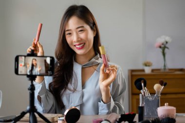 Ruj tutan ve makyaj vlogger kozmetik gözden geçirmek için ürün gösteren güzellik blogcusu.