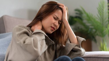 Guitar and singer concept, Young asian woman is feeling headache and neck pain after singing.